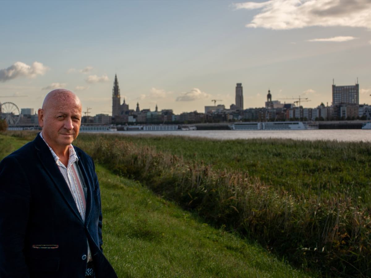 Marc Dassen op de Scheldedijk, met de skyline van Antwerpen achter zich.